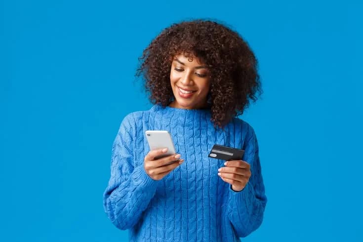 Smiling woman paying with her phone and card